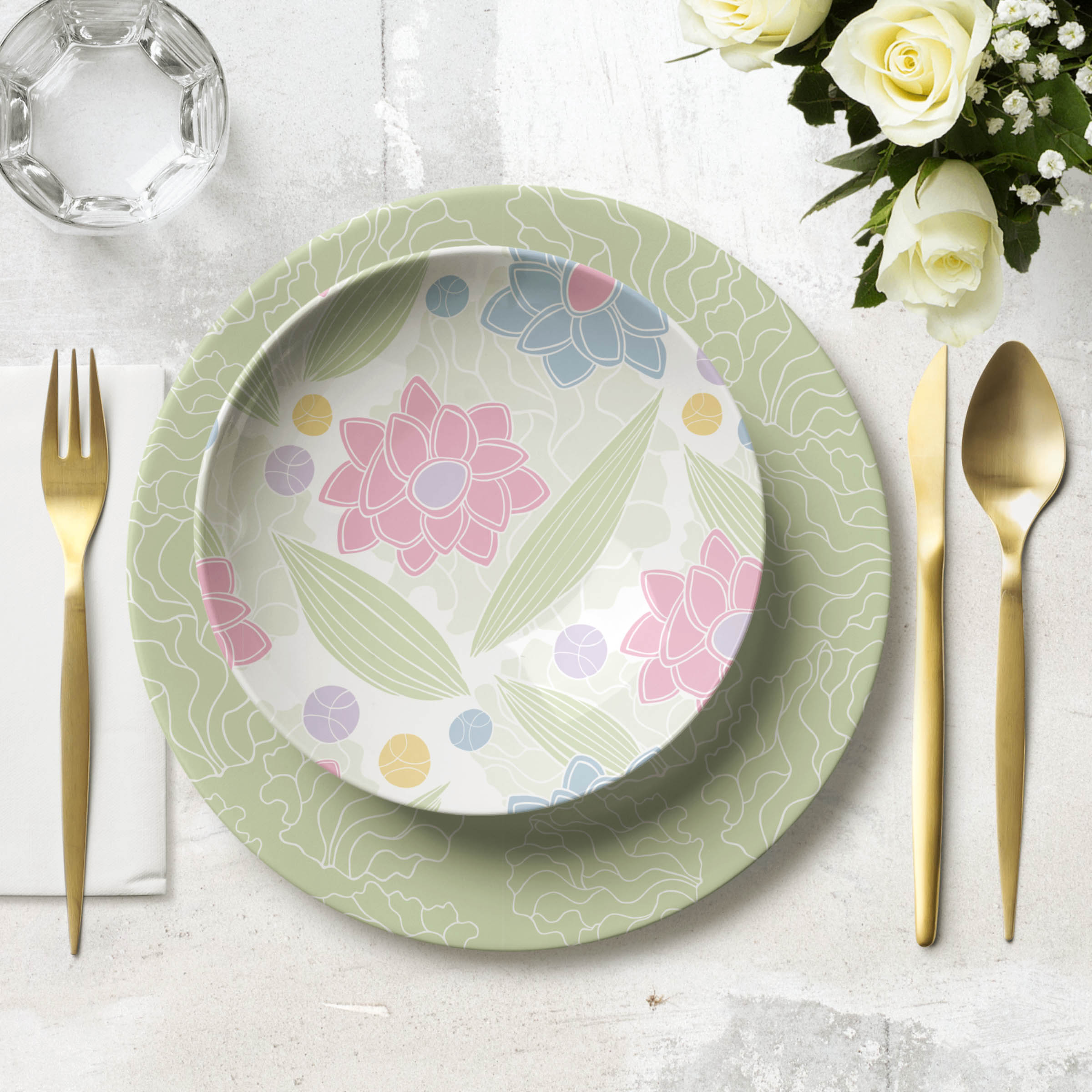 Bowl and plate with a gold fork on the left and a gold knife and spoon on the right. Glass on the top left and a bouquet of white roses on the top right of the image.